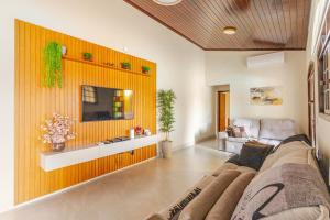 a living room with a couch and a tv on a wall at Casa moderna no Morada da Praia - Conforto, Estilo e Pet Friendly in Bertioga