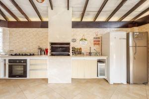 a large kitchen with a refrigerator and a stove at Casa moderna no Morada da Praia - Conforto, Estilo e Pet Friendly in Bertioga