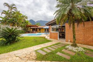 a house with a palm tree and a swimming pool at Casa moderna no Morada da Praia - Conforto, Estilo e Pet Friendly in Bertioga