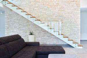 un salon avec un canapé et un mur de briques dans l'établissement Villa Dolcea Elegant Und Stilvoll Mit Pool, à Kaštel