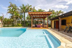 a swimming pool with a pergola next to a house at Casa moderna no Morada da Praia - Conforto, Estilo e Pet Friendly in Bertioga