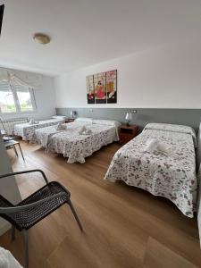 Habitación con 4 camas y una silla. en O Castelo, en Palas de Rei 