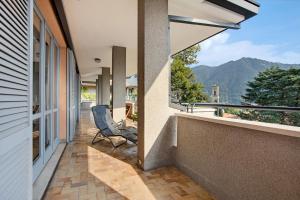 a balcony with a chair and a view of the mountains at Appartamento Il Parco Cernobbio in Cernobbio