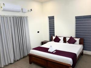 a bedroom with a large bed with purple pillows at Casa Linda Residency in Varkala