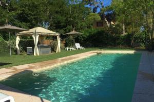 een zwembad in een tuin met een parasol bij Appartamento Papavero Seaside and Pool in La Caduta