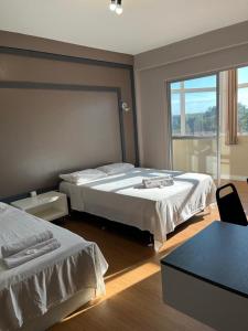 ein Hotelzimmer mit zwei Betten und einem Fenster in der Unterkunft Hotel Nossa Casa in Ijuí