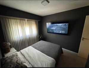 sypialnia z łóżkiem i telewizorem na ścianie w obiekcie Depto Comahue Playa Necochea w mieście Necochea
