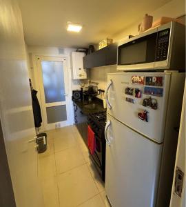 W kuchni znajduje się biała lodówka i kuchenka mikrofalowa. w obiekcie Depto Comahue Playa Necochea w mieście Necochea