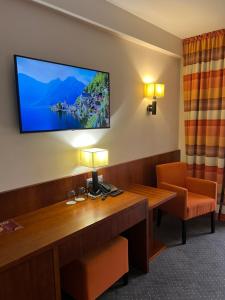 Habitación con escritorio y TV de pantalla plana en la pared. en Hotel Amadeus, en Wodzisław Śląski