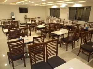 Un restaurante con mesas y sillas en una sala. en Ilva Hotel, en Lahore