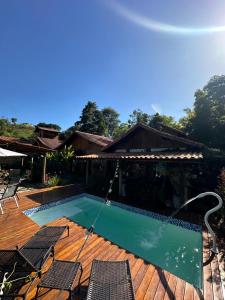 a swimming pool on a deck with chairs around it at Pousada Trilha das Àguas in Visconde De Maua