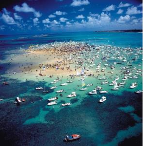 een groep mensen op een strand met boten in het water bij Apartamento Cabedelo - Intermares Beach in Cabedelo