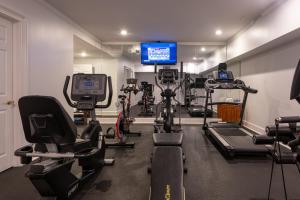 a gym with several tread machines and a tv at Saratoga Arms Hotel in Saratoga Springs