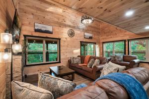 a living room with leather furniture in a log cabin at Smoky Mountain Cabin, Sleeps 12, 2 Kitchens & Hot Tub in Pigeon Forge