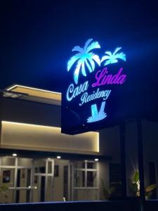 une enseigne lumineuse de restaurant avec des palmiers dessus dans l'établissement Casa Linda Residency, à Varkala