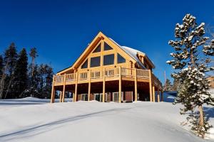 ein Blockhaus im Schnee mit einem Baum in der Unterkunft New Log Home, Hot Tub For 8, Views! in Tabernash