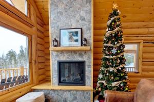 ein Weihnachtsbaum in einem Zimmer mit Kamin in der Unterkunft New Log Home, Hot Tub For 8, Views! in Tabernash