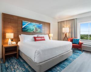Compass Hotel Beaufort by Margaritaville في Beaufort: غرفة فندقية بسرير كبير وكرسي احمر