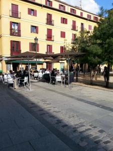 un grupo de personas sentadas en mesas frente a un edificio en Pension Antonio, en Madrid