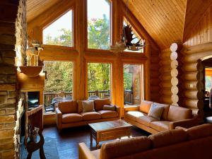 a living room with couches and a fireplace in a log cabin at Blue Moose Private pool spa sauna lake access in Wentworth
