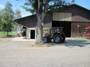 un tractor estacionado junto a un árbol al lado de un edificio en Farbhaus Bleiche, en Rohrbach