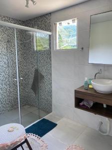 ein Badezimmer mit Glasdusche und Waschbecken in der Unterkunft Encantadora Casa Campeche in Florianópolis