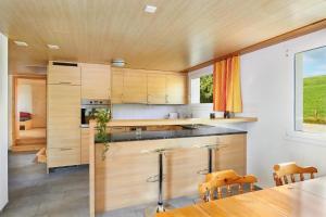 eine Küche mit Holzschränken und einem Tisch mit Stühlen in der Unterkunft Hof Höchi - b48796 in Bruggen