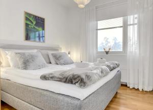 a white bedroom with a large bed with a blanket on it at Adorable Arctic Apartments - Private Sauna & Free Parking in Rovaniemi