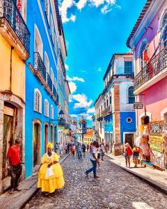 Une femme en robe jaune marchant dans une rue dans l'établissement Pelourinho House Experience, à Salvador