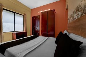 Un dormitorio con una cama con paredes naranjas y una ventana. en Collection O KSRTC Bus Station Kottayam Formerly Hotel O Day Springs, en Kottayam