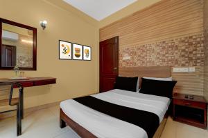 Un dormitorio con una cama, un escritorio y un espejo. en Collection O KSRTC Bus Station Kottayam Formerly Hotel O Day Springs, en Kottayam