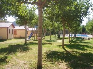 La Puebla de RodaGemütlicher Ferienbungalow Isabena的公园,公园内有种有树木的游乐场和滑梯