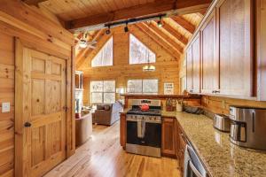 a kitchen with a stove and a living room at Elevated Cabin Bordering Smoky Mountain Nat'l Park in Bryson City