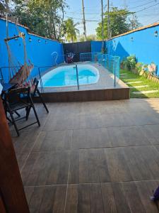 a swimming pool with a hammock next to a blue wall at Casa praia in Caraguatatuba