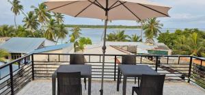 a balcony with a table and chairs and an umbrella at Fiya Inn in Maalhos