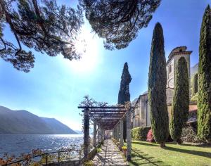 a building with trees in front of a body of water at Lakefront with garden in Oria
