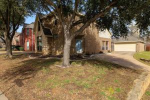 a stone house with a tree in the yard at Fenced Backyard - Workspace - Near DFW Airport in Euless