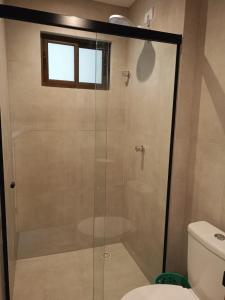 a glass shower in a bathroom with a toilet at Flat has rooftop with barbecue and sea view in Tamandaré