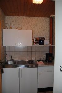 une cuisine avec des armoires blanches et un évier dans l'établissement Ländliche Ferienwohnung In Beliebtem Gästehaus, à Goosefeld