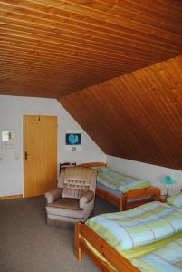 Cette chambre mansardée comprend 3 lits, une chaise et un canapé. dans l'établissement Ländliche Ferienwohnung In Beliebtem Gästehaus, à Goosefeld 1 autre photo