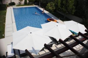 eine Gruppe weißer Sonnenschirme neben einem Pool in der Unterkunft Helle Ferienwohnung im Erdgeschoss mit privater Terrasse - b57950 in Splitska