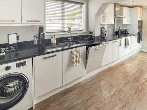 a kitchen with white cabinets and a washer and dryer at The Miners House in Deal +13 photos