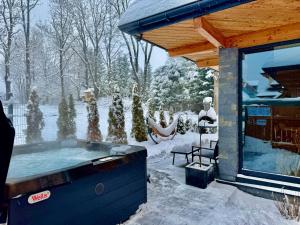 a hot tub outside of a house in the snow at Domki Siodemka 7a prywatne jacuzzi, sauna, 7b prywatne jacuzzi, sauna i klimatyzacja, wyposażenie zależy od wybranego domku in Zakopane