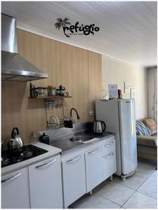 a kitchen with a white refrigerator and a sink at Refúgio Vibe do Mar in Barra Velha