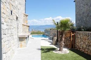 a house with a palm tree next to a stone wall at Villa Paradise in Vrbnik +22 photos