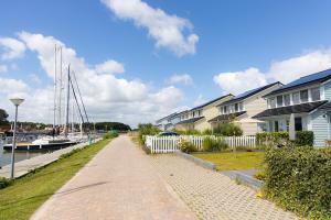 une promenade longeant des maisons et un port de plaisance avec des bateaux dans l'établissement Watervilla Den Oever VP066, à Wieringerwerf