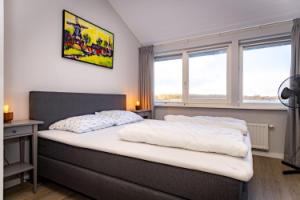 une chambre avec un lit avec des draps blancs et des fenêtres dans l'établissement Watervilla Den Oever VP066, à Wieringerwerf