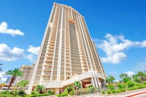 a tall building with palm trees in front of a blue sky at Solara Vita at MGM Signature in Las Vegas