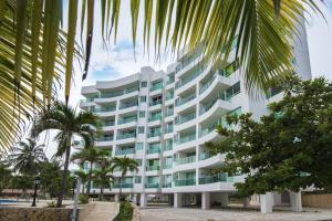 Estación El SaltoHermoso Apartamento Frente al Mar 3 Habitaciones MSC34的一座巨大的白色建筑，前面有棕榈树