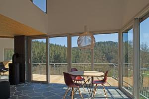 ein Esszimmer mit Tisch und Stühlen und Fenstern in der Unterkunft Kleines Vulkaneifelhaus in Schutz